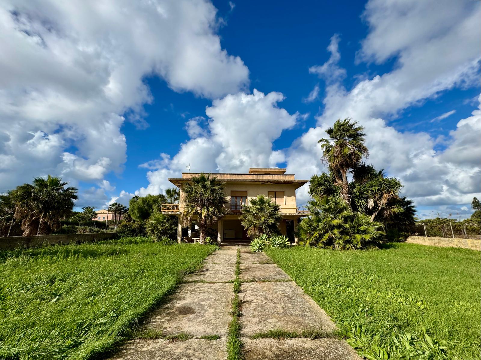 La Villa Organica exterior with palms and Sicilian sky
